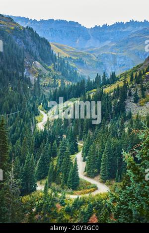 Winding dirt road in valley going through the mountains Stock Photo