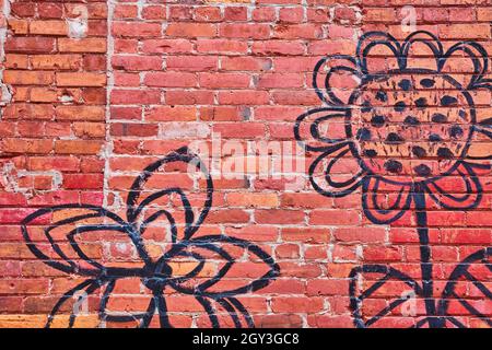Red brick wall texture with simple black flower artwork Stock Photo
