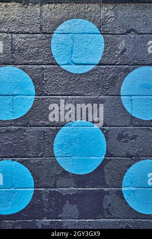 Vertical of black painted cement block wall up close with circles of blue Stock Photo