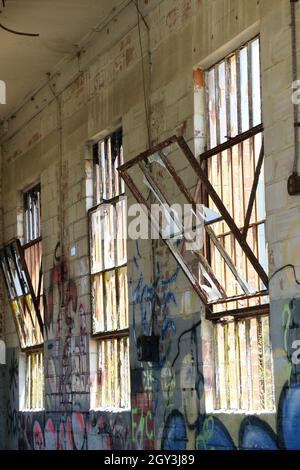 Rusted vintage hopper windows tilt inwards in an old, abandoned building. Stock Photo