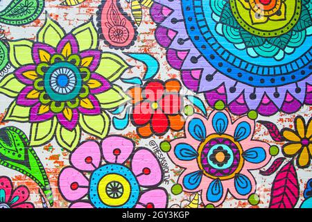 Rainbow colors of flowers on brick wall mural Stock Photo