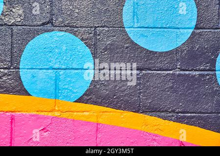 Painted cement wall with black, orange, and pink and blue circles Stock Photo