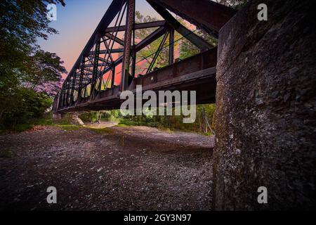 View by bridge support for train tracks with intense sunset pink color Stock Photo