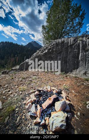 Close view of simple camp site in mountains with stone fire and stone wall Stock Photo