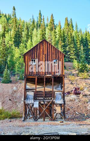 Old empty log mining structure with wall of mountains Stock Photo