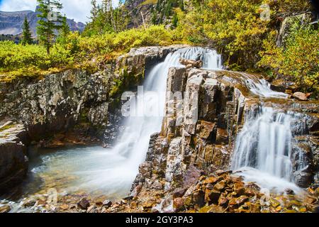 Close-up view of waterfalls into bucket of water with colorful rocks covered in lichen Stock Photo