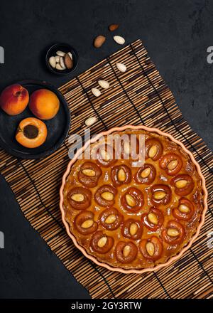 Delicious sweet apricot tart with almond nuts on dark background. Homemade food concept. Stock Photo