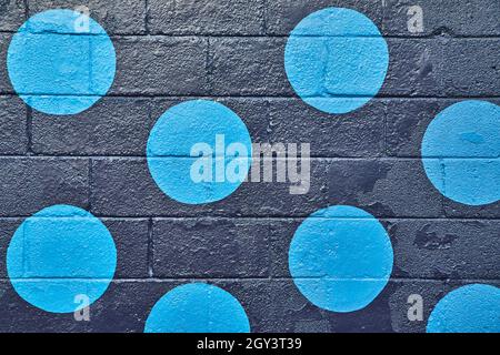 Black painted cement wall straight on with blue circles Stock Photo