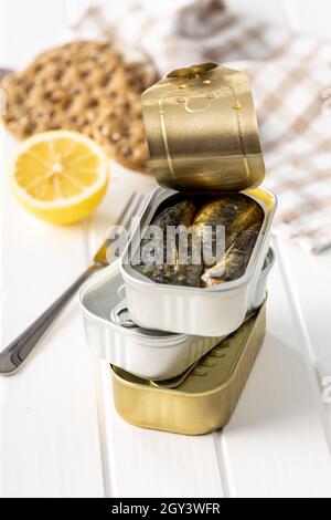 Canned sardines. Sea fish in tin can on white wooden table. Stock Photo