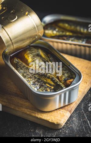 Canned sardines. Sea fish in tin can on black table. Stock Photo