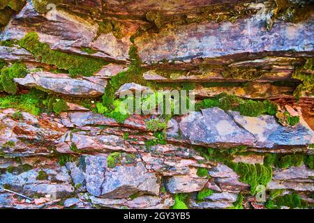Detail of canyon rock wall with red rocks and chunks of moss Stock Photo