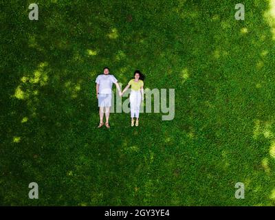 smiling couple laying down on green grass copy space Stock Photo