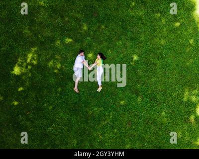 smiling couple laying down on green grass copy space Stock Photo