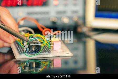 Manufacturing and setting up an electronic device in the laboratory. Soldering iron and electronic measuring instruments Stock Photo