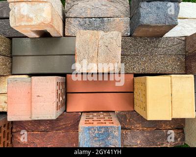 Different types of bricks stacked beautifully on green grass. Top view. Stock Photo