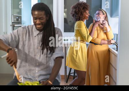 Multiethnic adult friends preparing food together at home in the kitchen Stock Photo