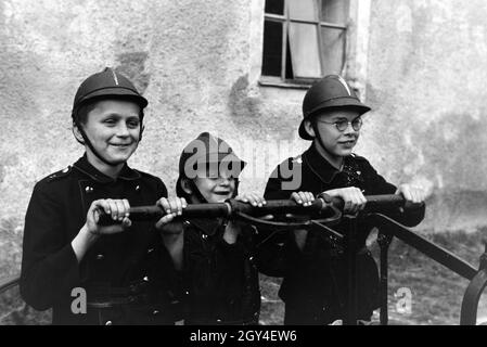 Jungen von der Kinderfeuerwehr betätigen bei einem Übungseinsatz die Wasserpumpe, Deutschland 1930er Jahre. Boys of the junior firefighters using the hand pump during a training, Germany 1930s. Stock Photo