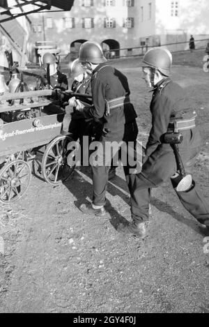 Eine Gruppe von der Kinderfeuerwehr mit dem Löschwagen bei einer Feuerwehrübung, Deutschland 1930er Jahre. A group of  junior firefighters is preparing the firewagon during a firefighter training, Germany 1930s. Stock Photo