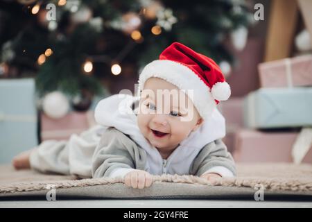 Adorable baby in red Santa hat on floor. Stock Photo