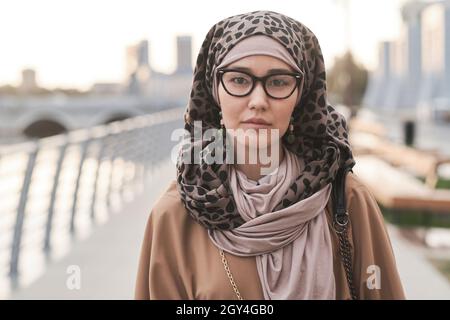 Portrait of elegant muslim woman in eyeglasses looking at camera while standing in the city Stock Photo