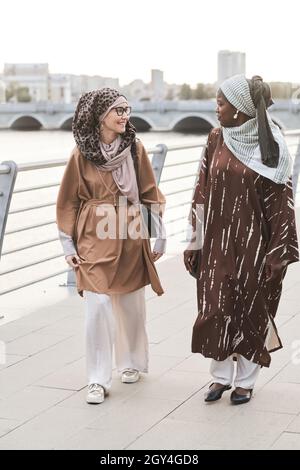 Two young muslim women talking to each other while walking in the city Stock Photo