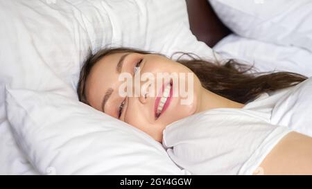 young woman wakes up and smiles at the camera Stock Photo