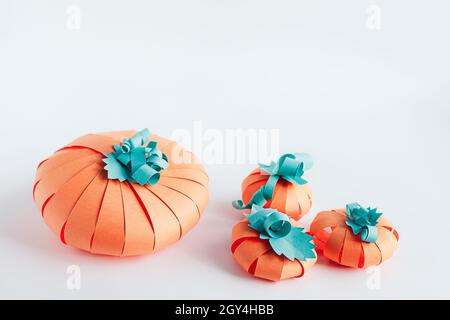 Some bright DIY paper pumpkins on gray background. Thanksgiving decor and Halloween craft idea for kids activities. Stock Photo