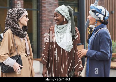 Three muslim women talking to each other and smiling during their meeting in the city Stock Photo