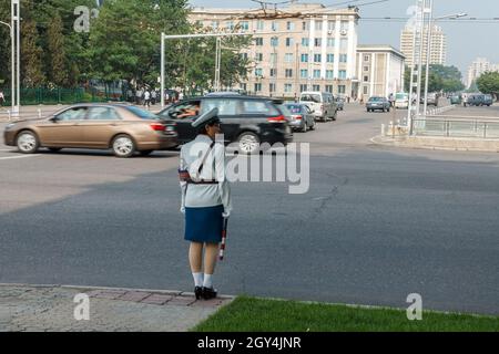 Pyongyang, North Korea - July 29, 2014: A girl policeman regulates traffic at a crossroads in Pyongyang. Pyongyang symbol. Stock Photo