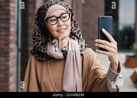 Elegant muslim woman using her mobile phone looking at camera she talking to her followers Stock Photo