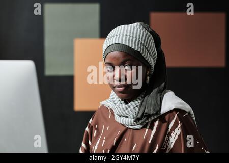 Close-up of Africa young businesswoman in hijab looking at camera while sitting at office Stock Photo