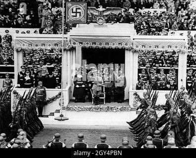 In the year of the outbreak of the Second World War, Adolf Hitler's birthday was celebrated with the largest military parade in German history. Adolf Hitler greets the passing units of the Wehrmacht with the Hitler salute. In the front row behind Hitler are Hermann Göring, Werner von Brauchitsch and Wilhelm Keitel. Guests in the VIP tribune include members of the military, SS and foreign state guests. [automated translation] Stock Photo
