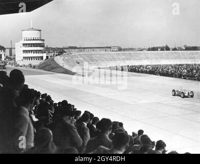 A car race took place on the Avus in Berlin on 28 May 1937. Here a driver (probably in a Mercedes-Benz W 25) passes the newly built and full grandstand after leaving the rebuilt north curve. On the left is the finish judge's tower. [automated translation] Stock Photo