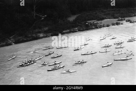 On Sunday, May 8, 1927, the Munich paddlers' associations opened the canoeing season with a squadron trip from Bad Tölz to Thalkirchen. In the very front three canoes have wedged themselves, in the middle one music is played. On the bank some walkers watch the scene. The Isar is in flood. [automated translation] Stock Photo