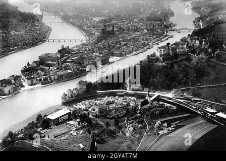 This undated aerial photograph was taken around 1935 above the Klosterberg (with the Salvatorian College) and shows the city of Passau at the confluence of the three rivers Danube, Inn and Ilz. After flowing past the church of St. Salvator and the town of Ilz (foreground), the black Ilz meets the waters of the blue Danube at Veste Niederhaus (centre of the picture). On the right is the Veste Oberhaus on the Georgsberg. The towers of the monastery church of Niedernburg, St. Michael, the town hall, the cathedral and St. Paul stand out from Passau's old town (from front to back). The Danube is Stock Photo