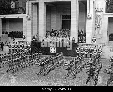 Adolf Hitler visited Italy, allied with Nazi Germany, at the beginning of May 1938. On Friday, May 6, 1938, a parade with 50000 soldiers and members of fascist organizations took place on the Via Trionfale (today Via di San Gregorio) in Rome. The picture shows the Balilla boys parading in rows, marching past the tribune with fanfares. On the tribune are (from left to right): Benito Mussolini, Adolf Hitler, King Victor Emmanuel III of Italy and his wife Elena of Montenegro. Behind them are other greats of both fascist states. [automated translation] Stock Photo