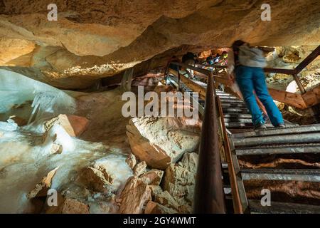 Tourists climbing a steep stairway inside the Dachstein Rieseneishöhle, a giant ice cave in the Austrian Alps, passing massive ice formations Stock Photo
