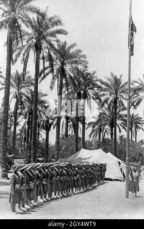 'A group of Young Fascists (Giovani Fasciste) took part in a ''Campo Roma'' in the Italian colony of Libya in 1938. They lined up in front of the pole with the Italian flag for the flag salute. Their uniform consists of pith uniform and pith helmet. [automated translation]' Stock Photo