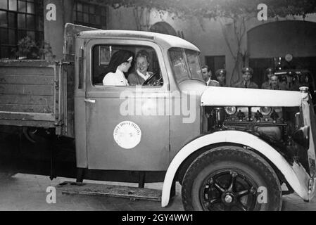 These two women are driving an ambulance of the Italian Red Cross. In the background some men are standing and watching them. The photograph was taken in 1940. [automated translation] Stock Photo