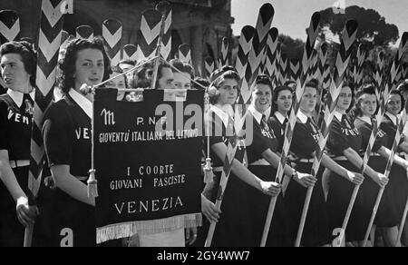 'Young women stand in front of an ancient building in the old town of Rome. The women belong to the ''Giovani fasciste'', the group of 18 to 21 year old women within the fascist youth organization Gioventu Italiana del Littorio. They are oarswomen from the local group from Venice. The banner bearer holds the group's banner with the inscription: ''M P.N.F. / Gioventú Italiana del Littorio / I Coorte / Giovani Fasciste / Venezia''. [automated translation]' Stock Photo