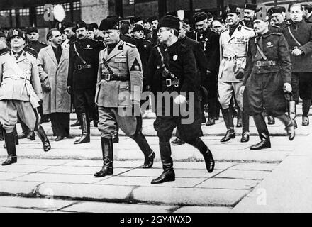 "On October 28, 1935, the 13th anniversary of the Fascist ""March on Rome"", Benito Mussolini, leader of the Partito Nazionale Fascista, walked through Rome to inaugurate a series of new public buildings in Rome. Here he is descending the steps of the Palazzo delle Poste e Telegrafi (now Palazzo delle Poste Roma Ostiense) on Via Marmorata, which he inaugurated earlier. He was accompanied by numerous old Fascist comrades-in-arms. [automated translation]" Stock Photo