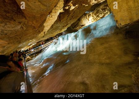 Tourists looking at a massive wall of ice inside the Dachstein Rieseneishöhle, a giant ice cave in the Austrian Alps, Salzkammergut Region Stock Photo