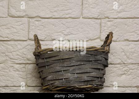 Empty wicker basket handmade close-up shot against brick light wall background Stock Photo