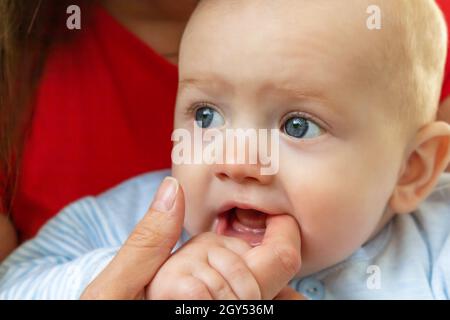 Little baby holding mother's finger in mouth. Stock Photo