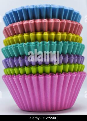 Stack of rainbow cup cake cases set against a white background Stock Photo