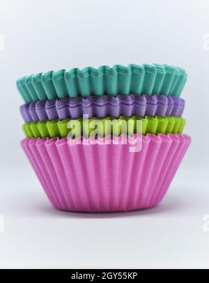 Stack of rainbow cup cake cases set against a white background Stock Photo