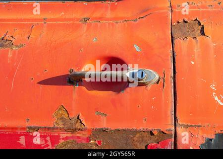 Old car door handle. Close-up photo of rusty red car door handle. Stock Photo
