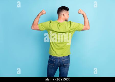 Back rear spine view photo of young happy man show muscles hands flexing isolated on pastel blue color background Stock Photo
