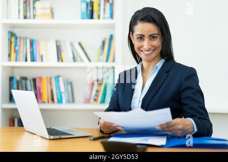 Beautiful hispanic mature businesswoman working with documents at desk at office Stock Photo