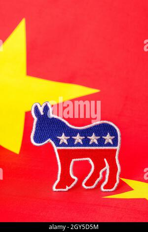 Dems / Democrat donkey logo set against a polyester red Chinese flag. For Democrat China ties, Hunter Biden China connections, Joe Biden China ties. Stock Photo
